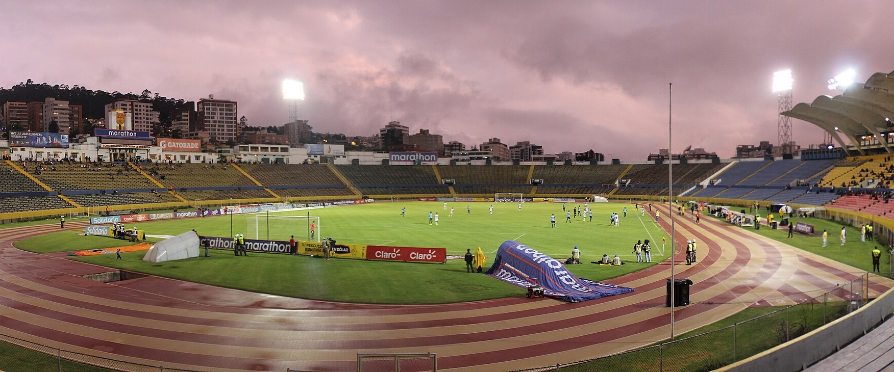 Panoramic view of Estadio Olimpico Atahualpa in Quito with floodlights on at dusk