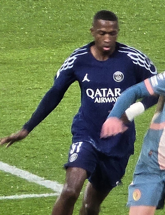 Willian Pacho in PSG's navy kit, number 51, on the ball against Manchester City